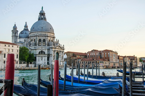 View of traditional gondolas on famous Grande Canal with historic Basilica di Santa Maria della Salute in the background in Venice, Italy