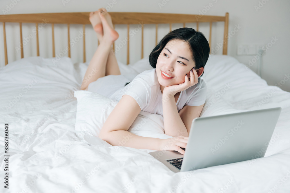 Young Asian girl using laptop in bed Young Asian girl using laptop in bed