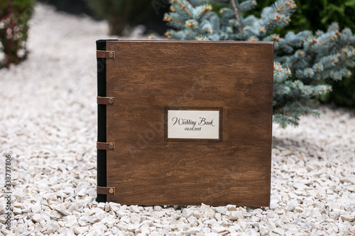 Photo book made of wood. Wedding photo album with wooden and leather cover is on a stone background in nature