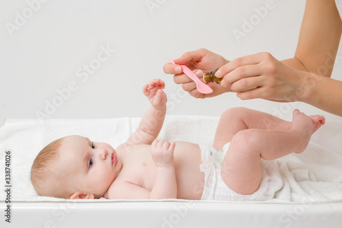 Принти на полотні Young mother hands holding pink plastic spoon and bottle of medicines