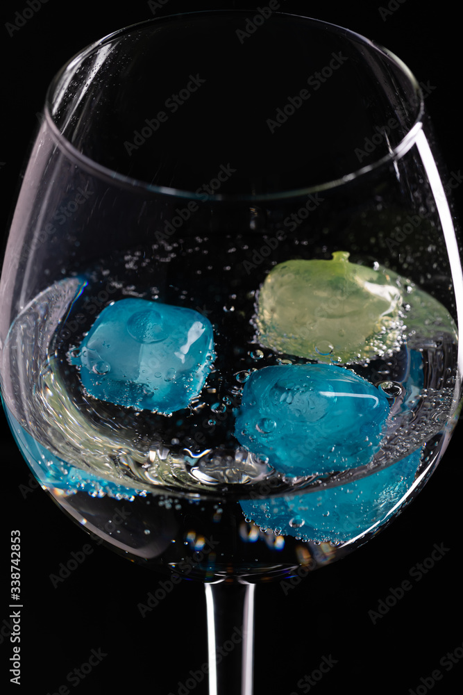 Wine glass with ice different colors on a black background.