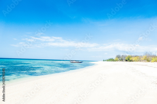 Beautiful tropical empty wild sandy beach with boat on a sunny summer day.