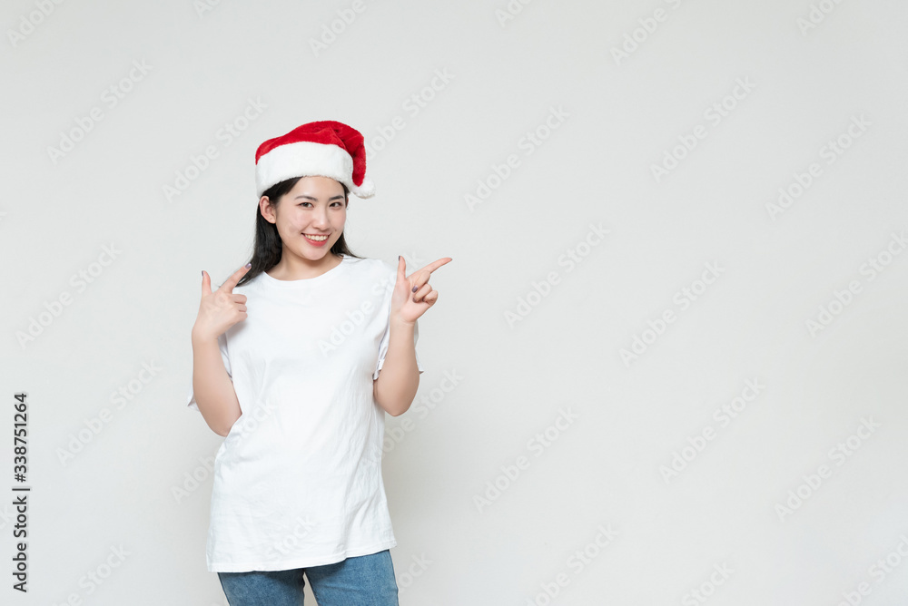 A young asian woman in a Christmas hat stands in front of the white wall A young asian woman in a Christmas hat stands in front of the white wall