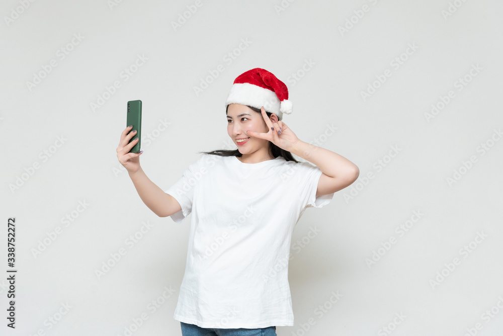 A young asian woman in a Christmas hat stands in front of the white wall A young asian woman in a Christmas hat stands in front of the white wall