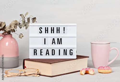 Pile of books, lightbox with the text, cup of coffee