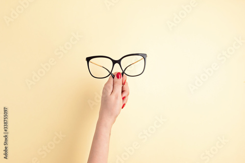 Woman hand holding eyeglasses. Optical store, glasses selection, eye test, vision examination at optician, fashion accessories concept. Top view