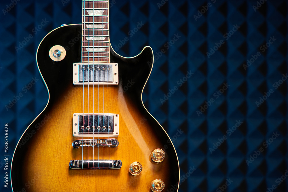 Fototapeta premium Sunburst electric guitar standing over acoustic foam panel background