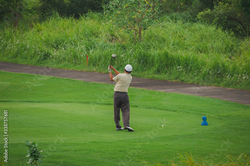 Golfer kicks the ball. Summer landscape - golf course.
