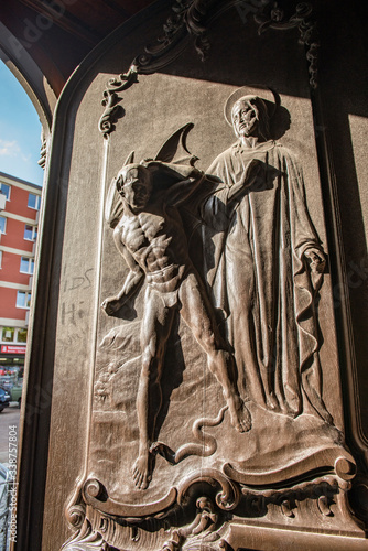 Geöffnetes Hauptportal an der Hamburger St. Michaelis Kirche mit kunstvollem Holzrelief - Darstellung einer Teufels- oder Satans-Gestalt mit einer Schlange, die vor Jesus Christus zurückweicht photo