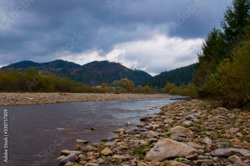 shore of a mountain river and thunderclouds