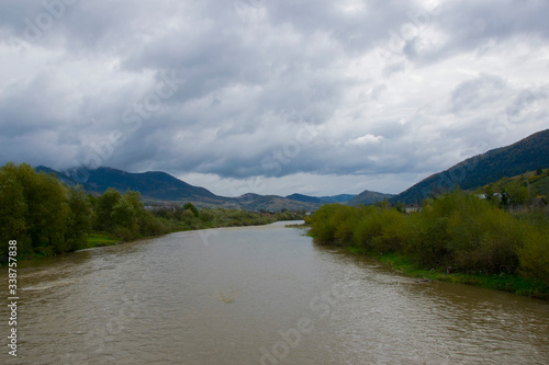  shore of a mountain river and thunderclouds