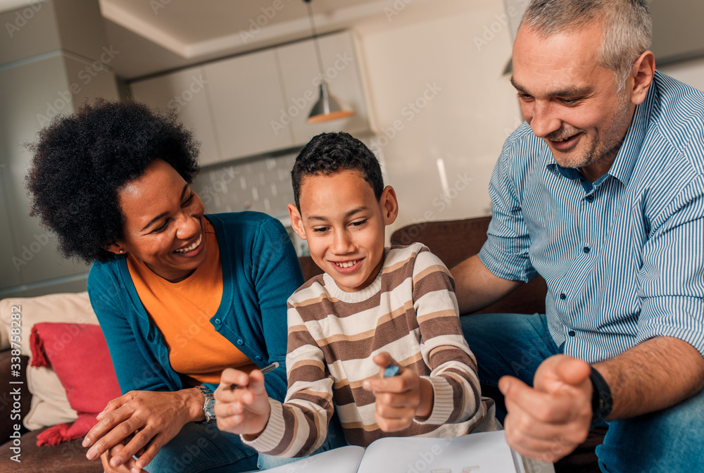 Obraz premium Parents helping their son with his homework at home in living room.