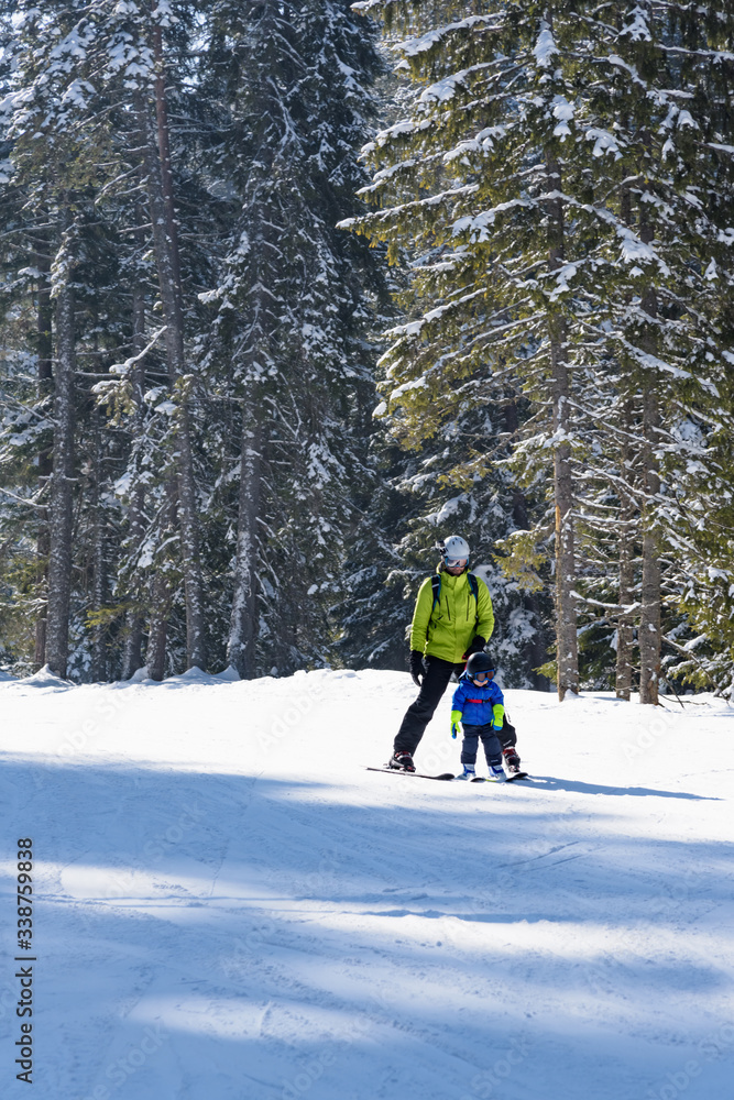 dad teaches his little son to ski