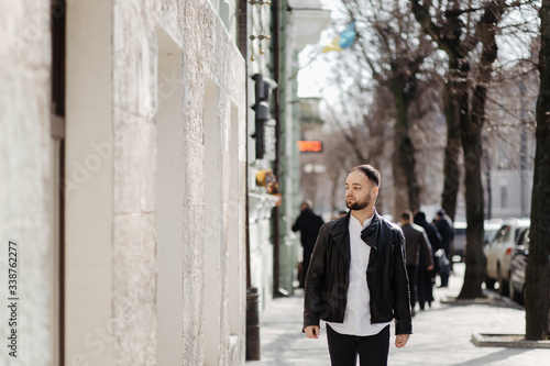 Portrait of fashionable well dressed man with beard posing outdoors