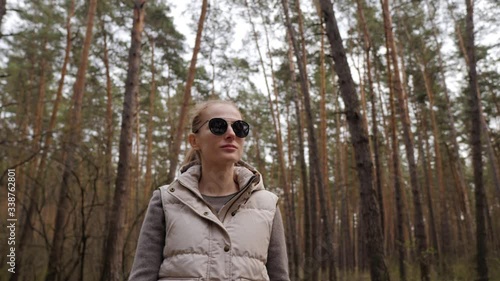 Beautiful woman in jacket waistcoat walk alone trailpath in pine forest in 4K photo