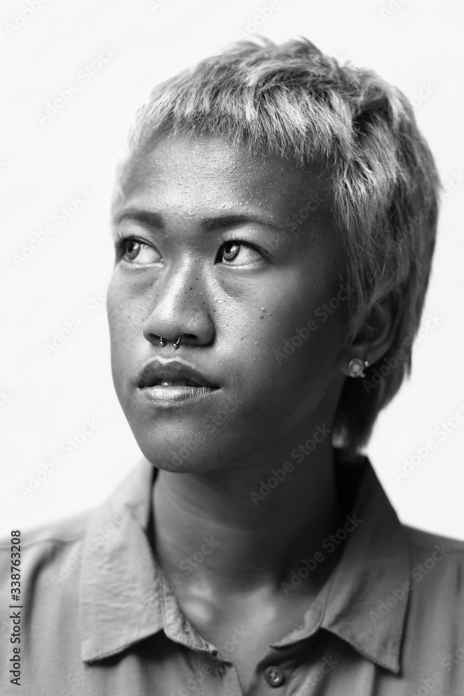 Face of young rebellious Asian woman with short hair thinking