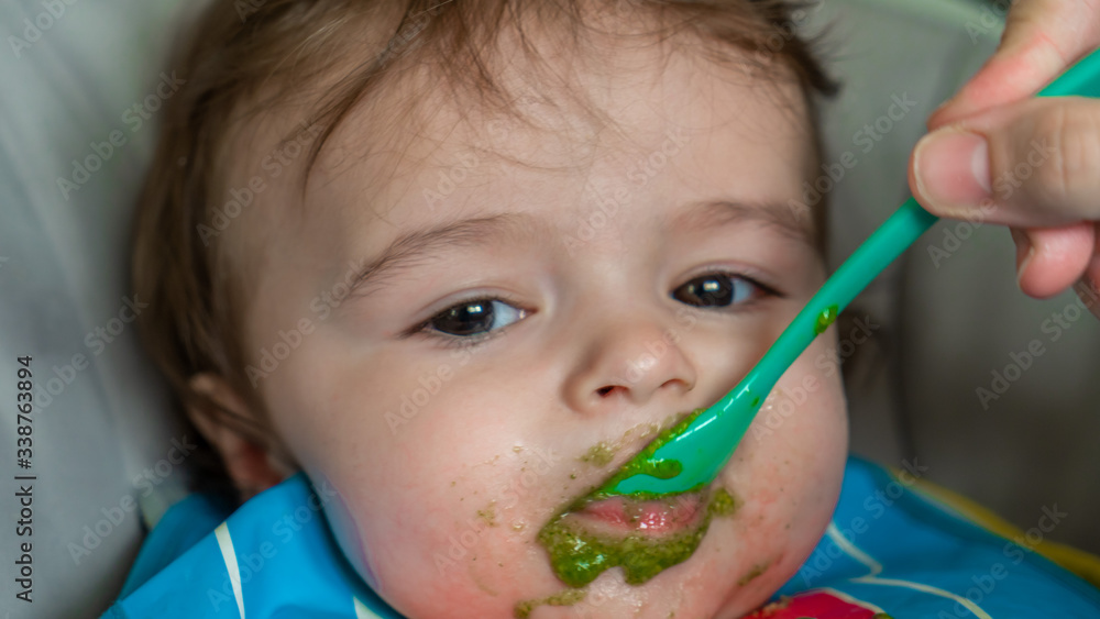 mother feeding her baby boy with a spoon mother feeding her baby boy with a spoon