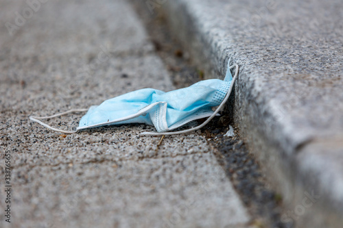 Close-up image of a surgical mask dropped and abandoned in the street during the coronavirus crisis in 2020.