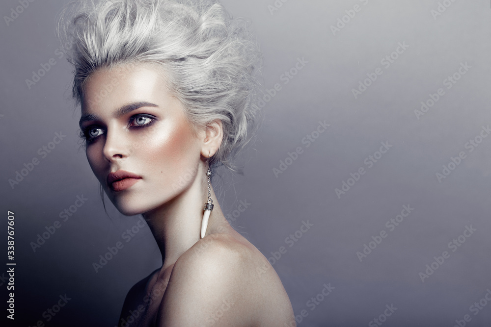 Profile of gorgeous young model with gray hairstyle, naked shoulders, makeup, smokey eyes, isolated on grey background.