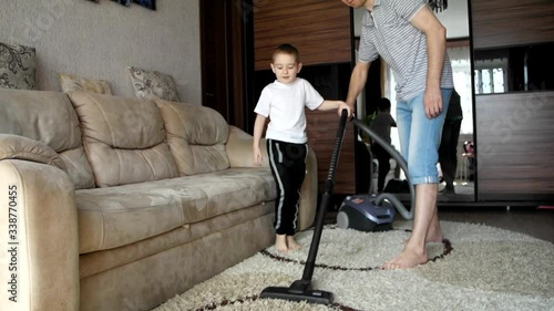 Father and son clean a house with a vacuum cleaner. A man and a boy do housework. Joint pastime, useful activities for children and parents. The family spends leisure time together.