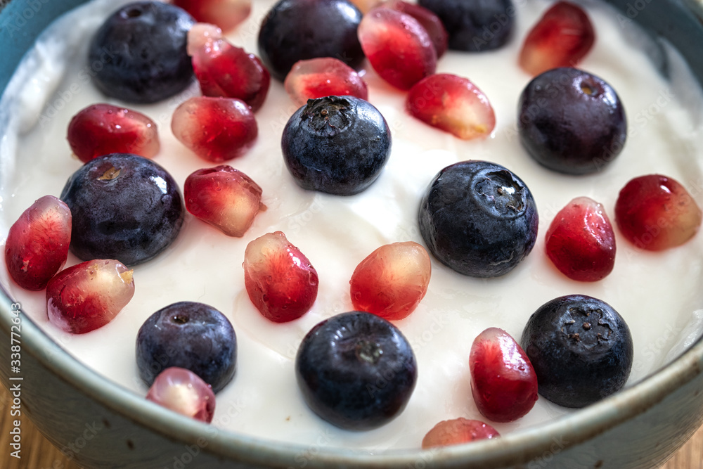 Bowl of yogurt, fresh blueberries, and seeds of pomegranate . Healthy breakfast, close up Bowl of yogurt, fresh blueberries, and seeds of pomegranate . Healthy breakfast, close up