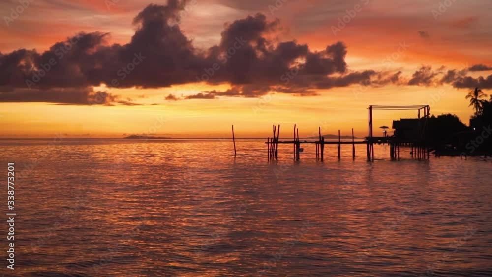 The beautiful after glow from a sunset in Asia. In the foreground there is a jetty with people relaxing The beautiful after glow from a sunset in Asia. In the foreground there is a jetty with people relaxing