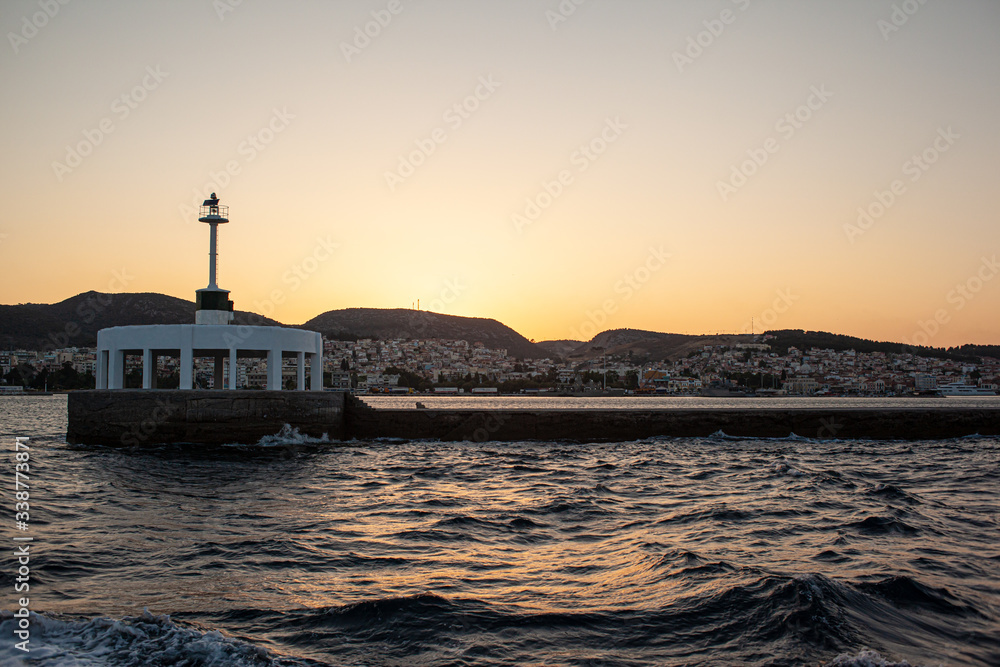 Harbor entrance in Greece with lighthouse at sunset