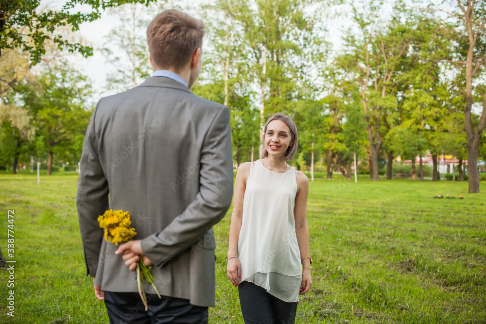 Happy girl looking at boy with flowers outdoor Happy girl looking at boy with flowers outdoor
