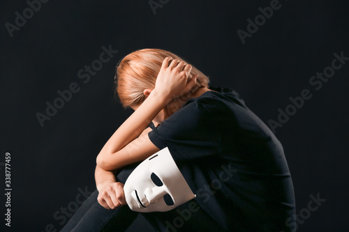 Woman holding mask on dark ...