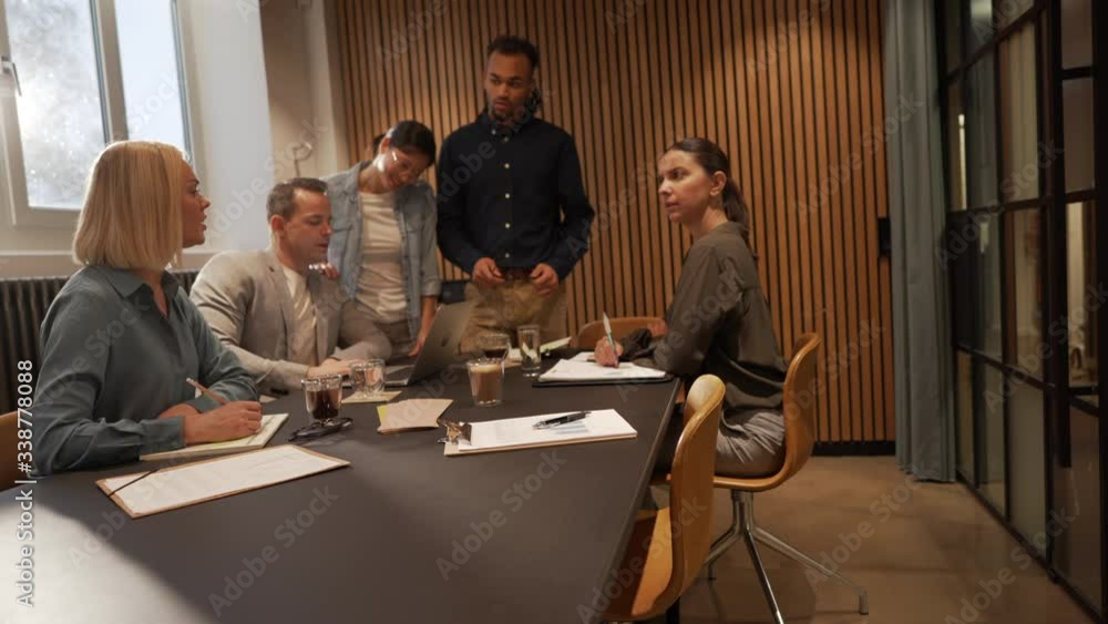 Diverse businesspeople working on a laptop and discussing a project during a meeting in an office boardroom Diverse businesspeople working on a laptop and discussing a project during a meeting in an office boardroom