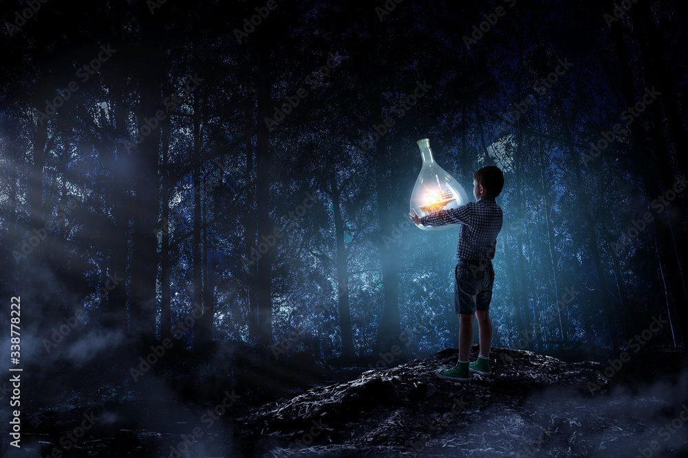 Obraz premium Boy holding glass flask with landscape inside it