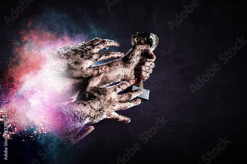 Hand holding up a gold trophy cup against dark background