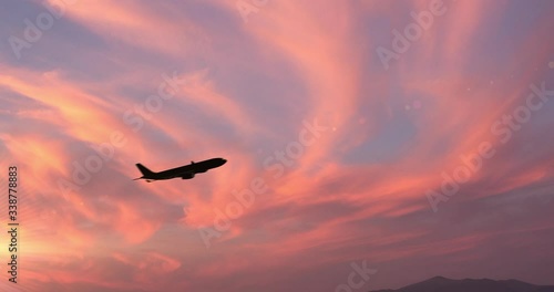 Vista laterale di un aereo passeggeri al decollo di fronte a un tramonto photo