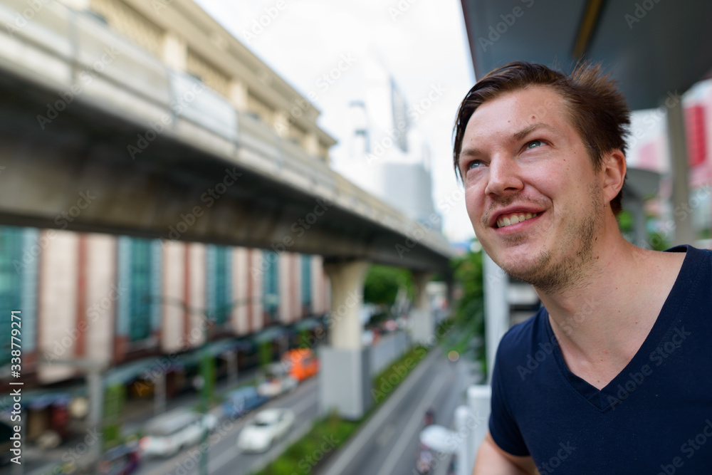 Face of happy young handsome man looking up at sky train station Face of happy young handsome man looking up at sky train station