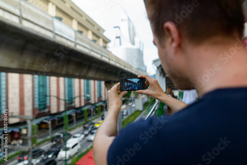 Closeup rear view of young man taking picture of the city streets with phone