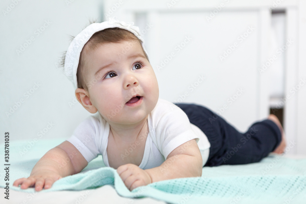Baby girl lying on bed with white bandage on her head, Caucasian infant portrait Baby girl lying on bed with white bandage on her head, Caucasian infant portrait