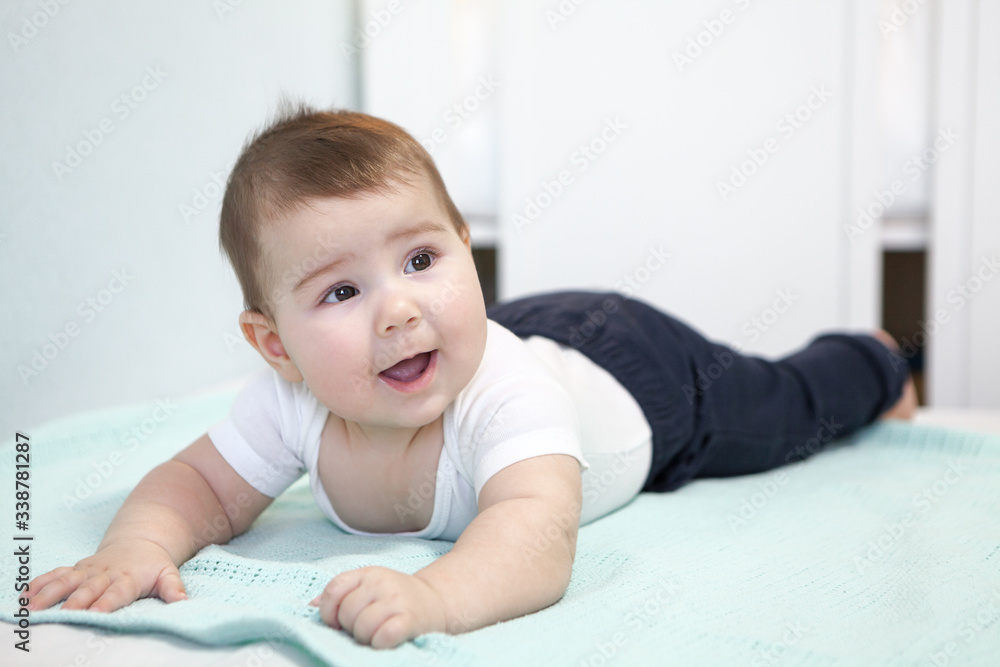 Baby boy trying to crawl on belly in a bed, smiling infant portrait Baby boy trying to crawl on belly in a bed, smiling infant portrait