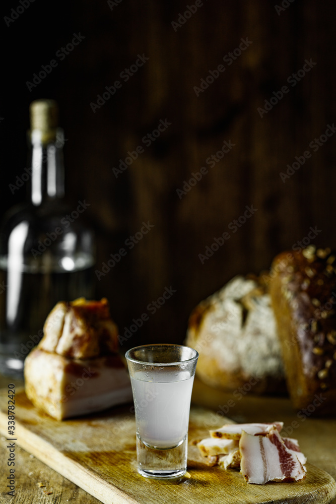 rye bread, lard, vodka, a glass of vodka on a cutting board on a wooden table and on a black background, rustic style