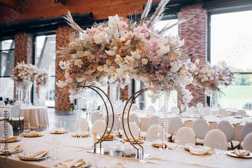 A large floral arrangement of an unusual shape stands on a beautiful festive table on the wedding