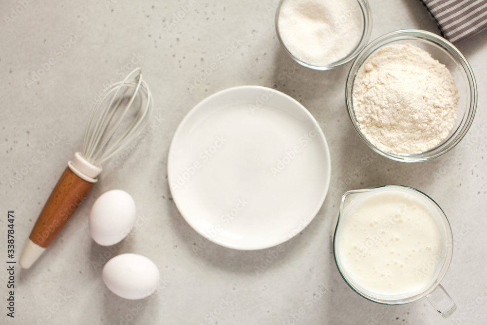 Ingredients for baking with flour and a cooking whisk with an empty white plate. The concept of food Ingredients for baking with flour and a cooking whisk with an empty white plate. The concept of food