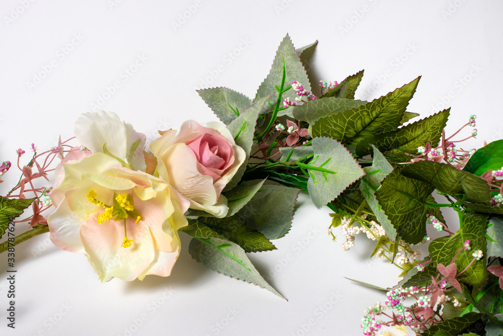 Fototapeta premium Artificial flowers on a white background. Pink and yellow roses.