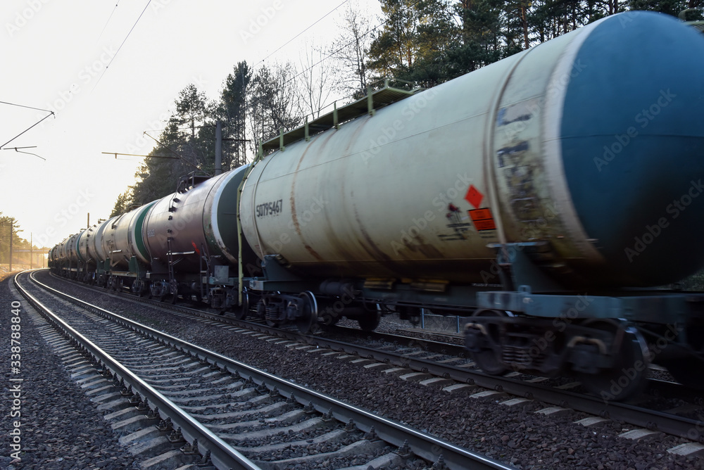 Freight train with petroleum tank cars on railroad. Rail cars carry oil and ethanol. Railway logistics transportation of methanol, crude and gas. Object in motion, soft focus, possible graininess Freight train with petroleum tank cars on railroad. Rail cars carry oil and ethanol. Railway logistics transportation of methanol, crude and gas. Object in motion, soft focus, possible graininess