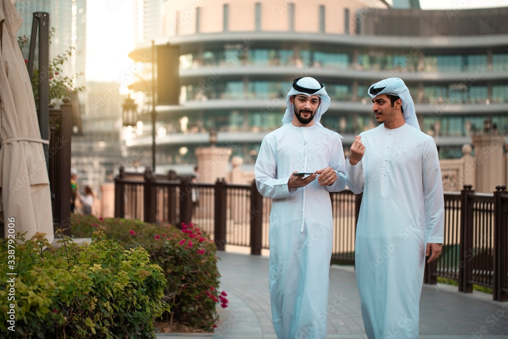 two Arab man wearing traditional clothes and walking in downtown 