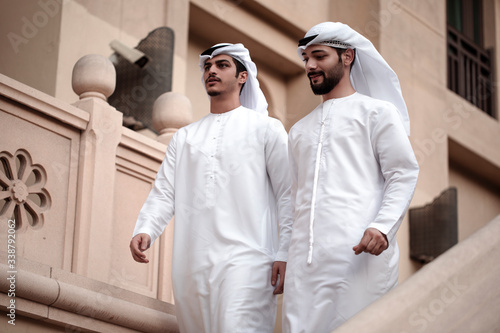 two Arab man wearing traditional clothes and walking in downtown 