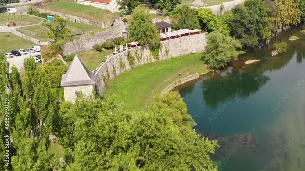 Aerial flight over green tree near lake, turret, and stone wall, Gorec, Bosnia Aerial flight over green tree near lake, turret, and stone wall, Gorec, Bosnia