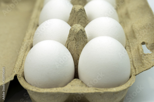 White chicken eggs in paper packaging close-up, soft focus.