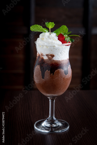 Chocolate milkshake  decorated with whipped cream and strawberries.