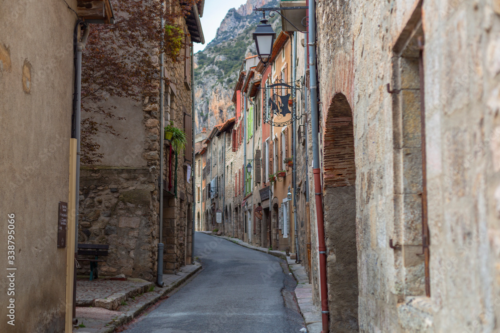 A narrow street with some color houses in a medieval town of France