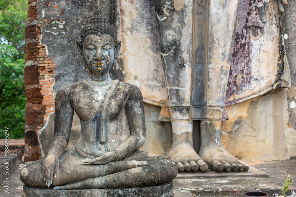 Two buddha sculptures, one sitting and the other standing, in Sukhothai, Thailand