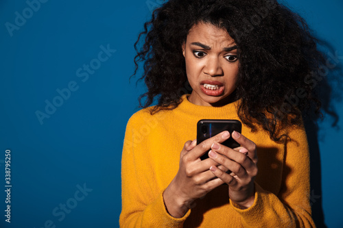 Confused african woman using mobile phone.